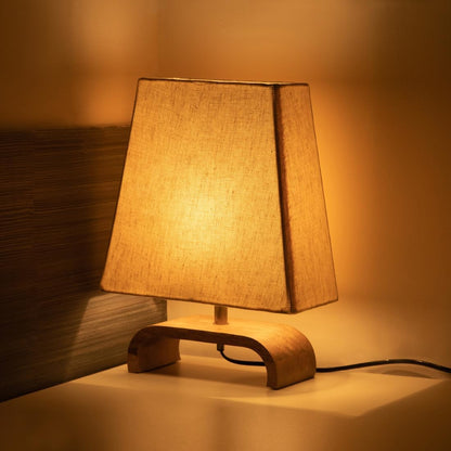 Wooden table lamp with a warm light on a wooden surface.