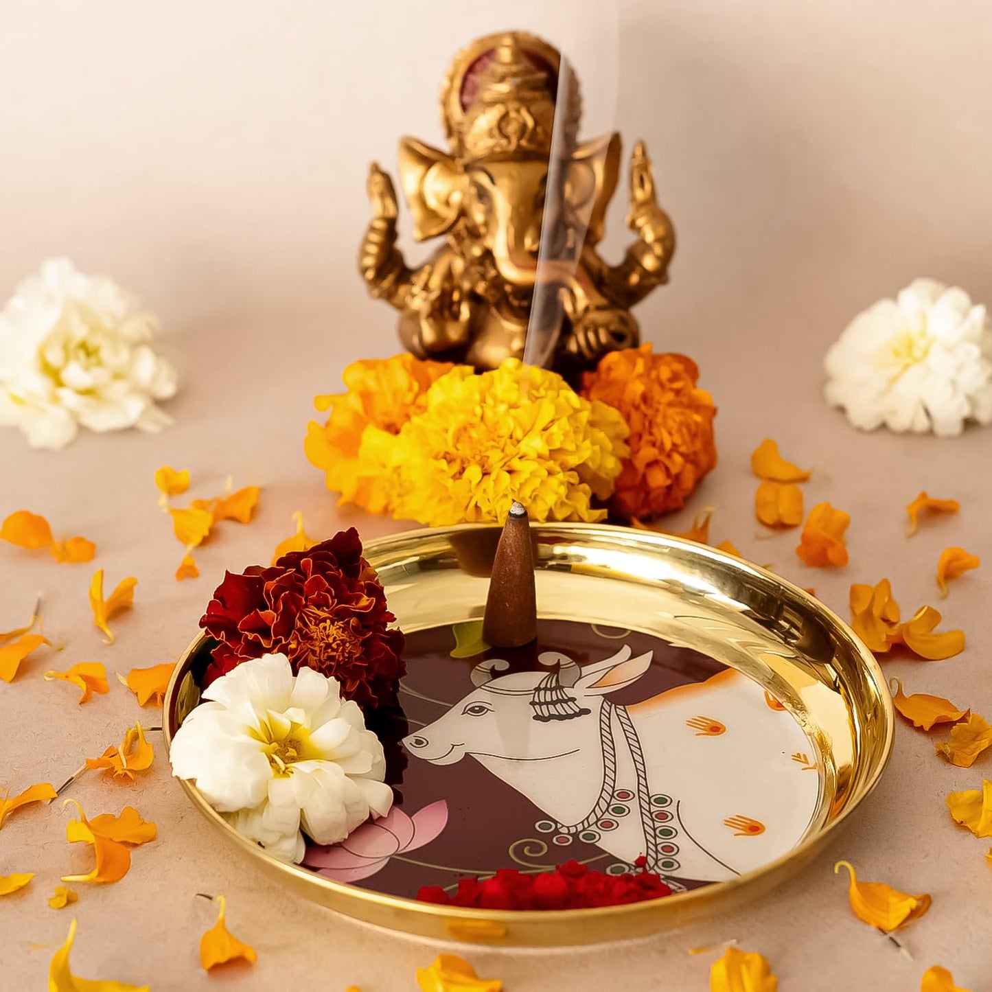 Decorative tray with a cow illustration, flowers, and a small statue on a beige background