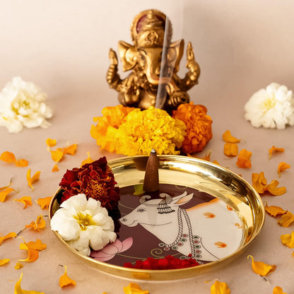 Decorative tray with a cow illustration, flowers, and a small statue on a beige background